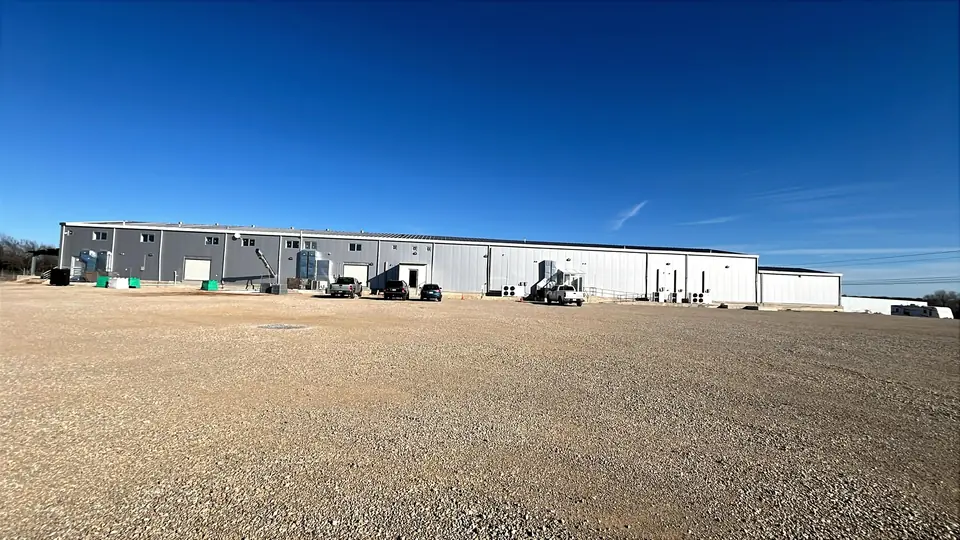 Gravel drive leading to the Creek Ranch plant under a clear North Texas sky